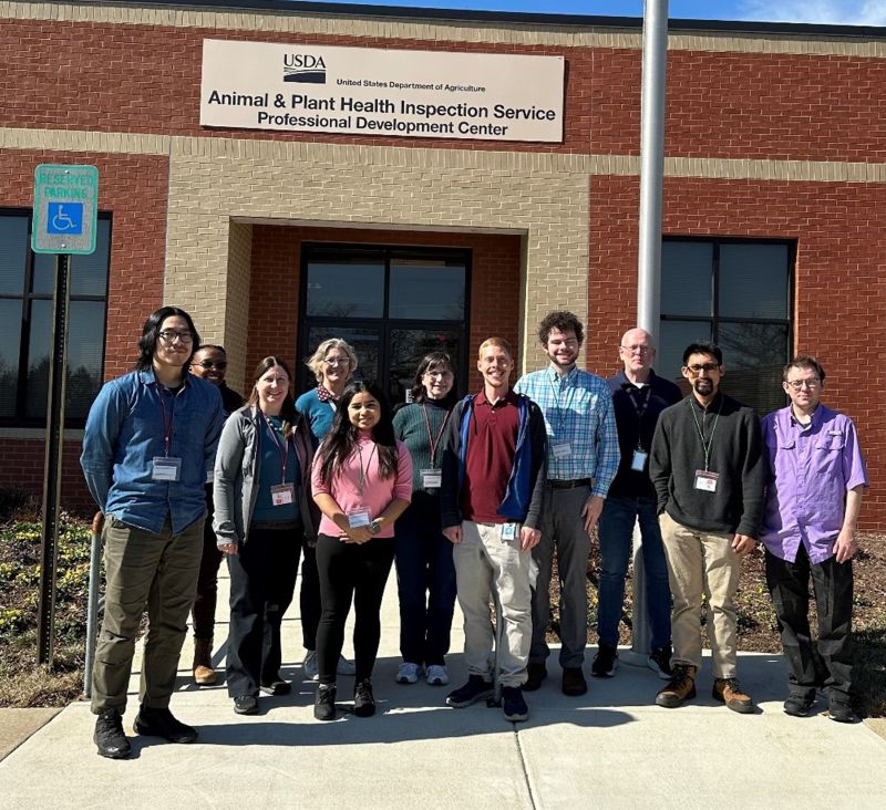 A group of people wearing business casual attire in front of a brick building.