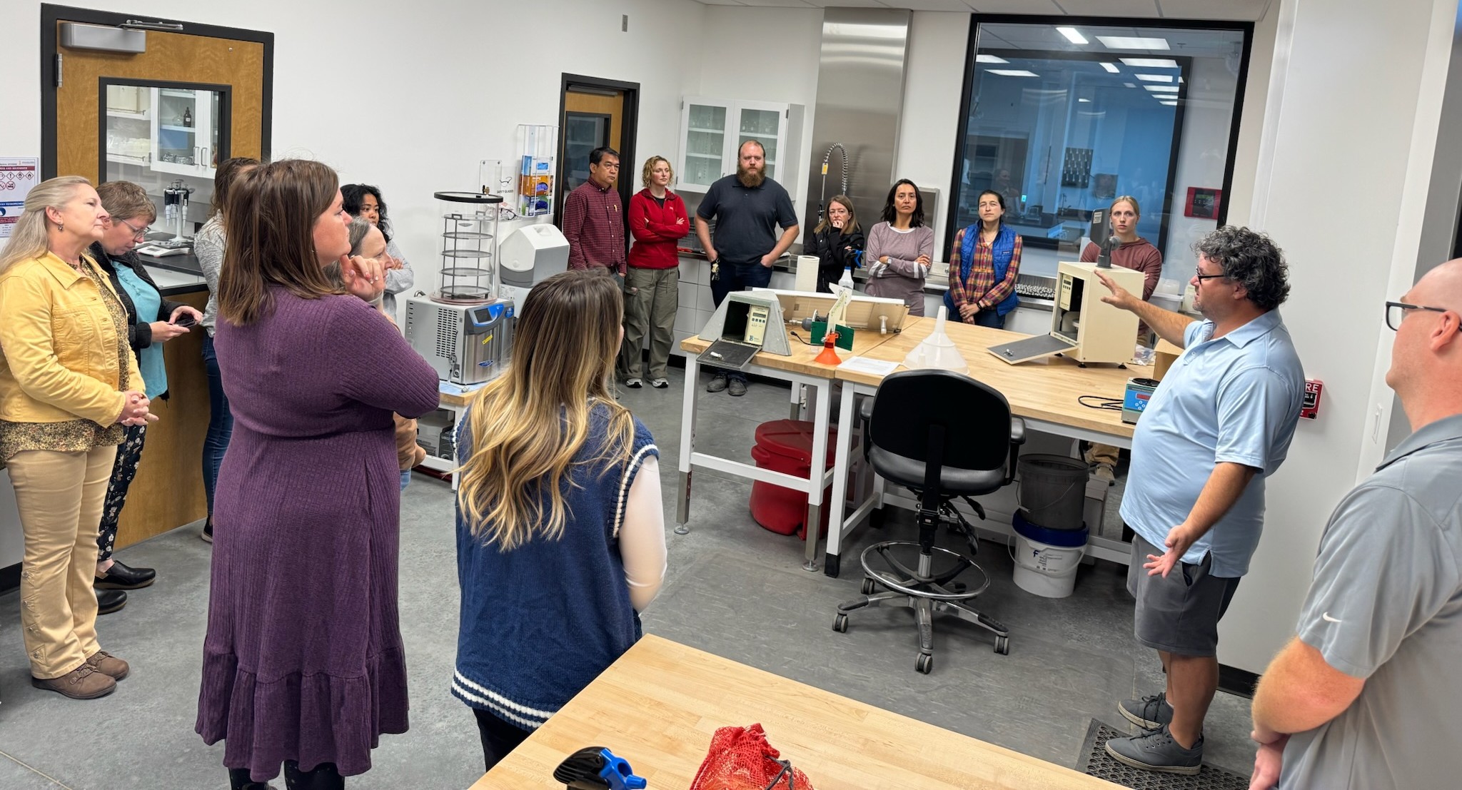 A group of diagnosticians gather around a speaker in an lab