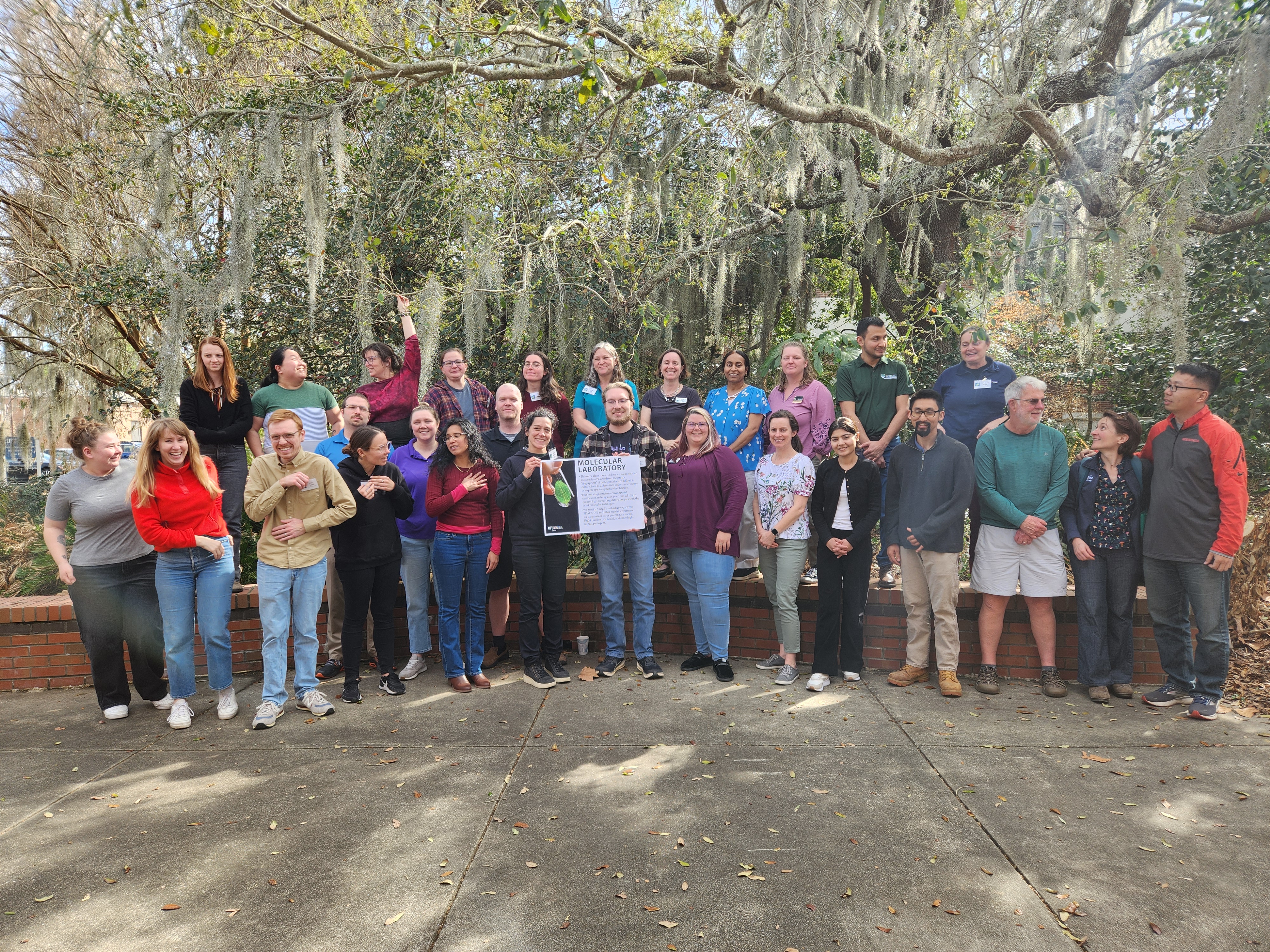 A group of people posed standing and holding a sign